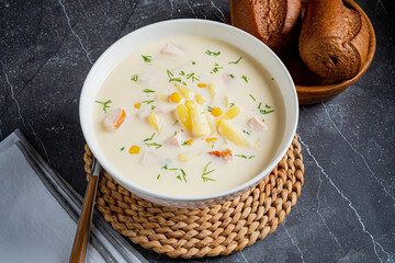 Creamy chicken and corn chowder, garnished with herbs and served with fresh rolls