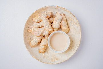 Sweet golden pastries dusted with powdered sugar, served alongside a smooth creamy dip for a treat