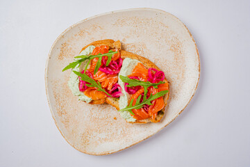 Open-faced sandwich with smoked salmon, herb spread, and vibrant veggies for a tasty meal