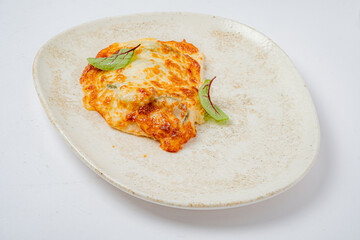 A deliciously baked dish adorned with melted cheese and vibrant green herbs invites appetites