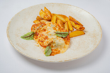 Juicy chicken breast covered in rich cheese alongside crispy potato wedges and herbs