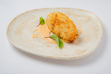 Delightful crispy treat rests on an artistic plate, garnished with sauce and fresh greens