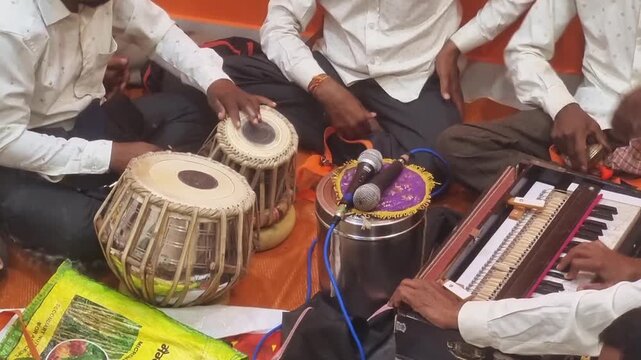 This Bhajani Mandal likely tunes tabla and harmonium for a Ganesh Chaturthi pooja ceremony, preparing to perform devotional music for the auspicious Hindu festival celebration.