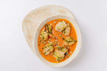 Crispy vegetable pieces are artfully arranged in a rich orange sauce, garnished with seeds