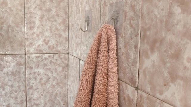 A woman wipes her wet hands with a terry towel hanging on a hook in the bathroom.