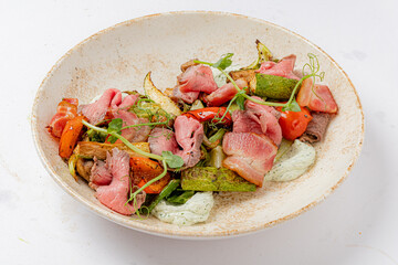 Tender roasted meats paired with vibrant grilled vegetables and fresh herbs create a colorful feast