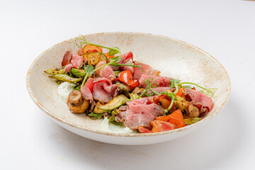 A colorful mix of roasted veggies and tender meat, topped with fresh greens, awaits you