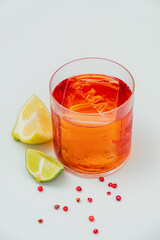 Chilled cocktail in a stylish glass, garnished with lime, lemon, and pink peppercorns