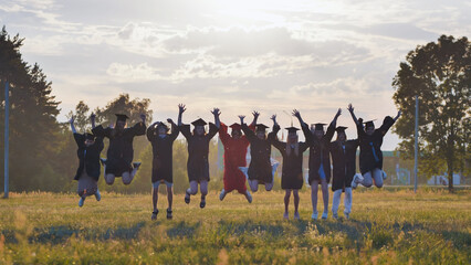 Energetic graduates celebrating their academic achievement in a sunlit field, jumping for joy