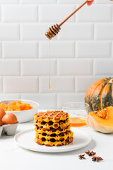 Autumn breakfast with pumpkin waffles and dripping honey. Pumpkin recipes.