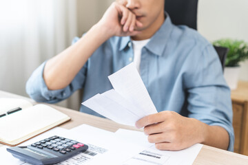 Debt and financial concept, stressed asian young man have a headache while male sitting calculate...
