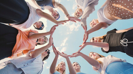 School friends coming together to form a united circle under a clear blue sky, representing...