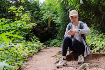 Hiker checking smartwatch on tropical forest trail