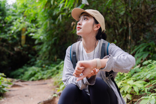 Hiker checking smartwatch during trekking in lush forest
