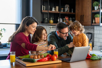 Parents and child relaxing at home with computer watching funny internet video, making online call