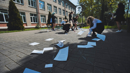 Female students cleaning up papers in the schoolyard on the last day of school