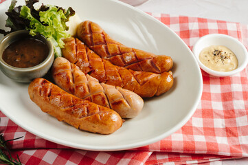 Grilled Sausages with Mashed Potatoes and Sauces on a White Plate