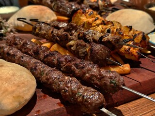 Delicious grilled kebab skewers with pita bread and chicken ready to serve on a wooden board