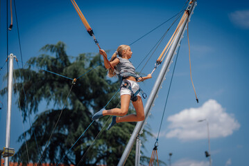 Girl jumping on bungee trampoline having fun in amusement park