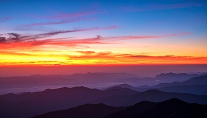 Vibrant sunset paints the sky with fiery hues over layered mountain ranges.