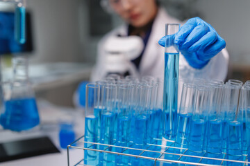 Scientist holding test tube with blue liquid in laboratory