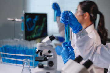 Scientists analyzing blue liquid in test tube in laboratory