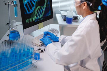 Scientist typing on keyboard analyzing dna structure on computer in laboratory