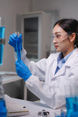 Scientist holding test tube with blue liquid in laboratory research experiment