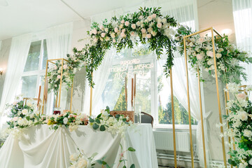 An elegant wedding hall with white curtains, gold elements and exquisite floral decor. An atmosphere of tenderness and romance, ideal for a celebration.