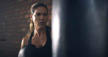 Woman, boxer and punching bag at gym with training, routine and intense workout for fitness....