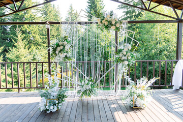 The wedding arch is decorated with white flowers and greenery, suspended on a terrace overlooking...