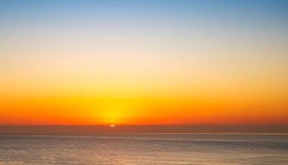 Obraz premium Stunning sunset over a calm ocean, vibrant colors paint the sky and water.