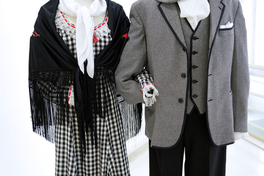 Traditional Madrid chulapo and chulapa costume with checkered patterns, shawl, scarf, and fitted suit.