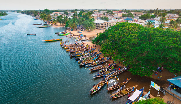 Aerial view of boats clustered along the sandy riverbank under the bright sun, a vibrant scene of coastal life, Grand-Popo, Mono, Benin.