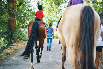 Children riding horses with instructor on country trail