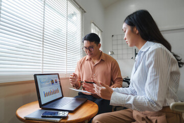 Business people analyzing financial charts on laptop in office meeting