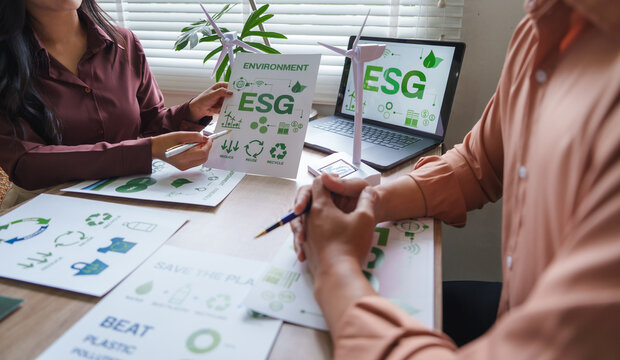 Managers discussing esg environmental social and corporate governance with charts and wind turbine models
