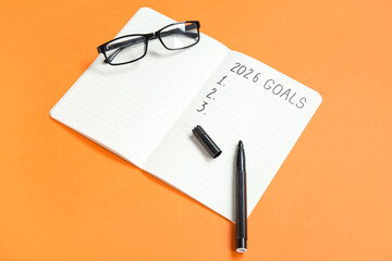 Notebook with empty to do list, eyeglasses and marker on orange background. New year goals