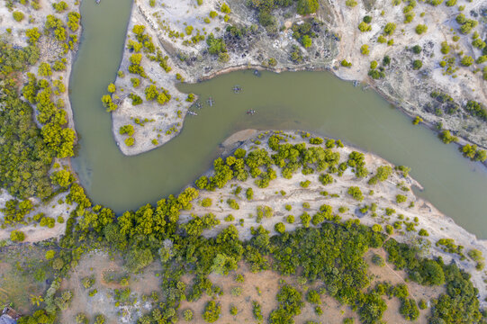 Aerial view Kongo river snaking through a landscape dotted with vibrant green trees against the backdrop of sandy terrain, Tiwi, Kwale County, Kenya.
