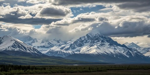 Majestic snow capped mountain peaks pierce through dramatic swirling clouds under a vast moody sky creating a breathtaking natural landscape