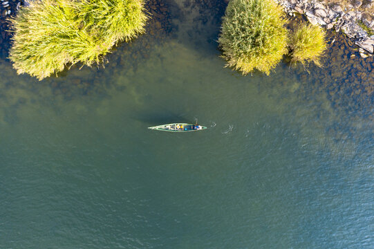 Aerial view of a lone kayaker glides through shimmering waters, framed by the rugged shoreline and verdant vegetation, Takawiri Island, Homa Bay, Kenya.