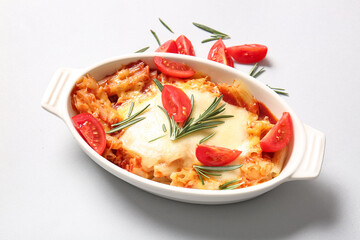 Baking dish of pasta with tomato sauce and cheese on white background