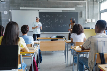 Hispanic student presenting a project reading a presentation to classmates and teacher at High...