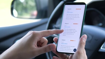 Close-up of a man in the driver's seat of a parked car, using a smartphone to research fuel stations on a review and rating app. He carefully reads user feedback and ratings, then confidently selects - Powered by Adobe