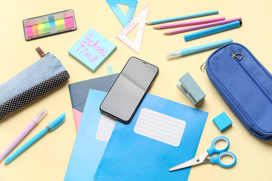 Sticky note with text SCHOOL TIME, different stationery and mobile phone on yellow background