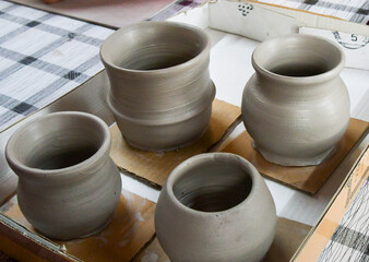 Hands in motion shaping clay on the potters wheel. Moment of creation at the wheel and ready pottery.