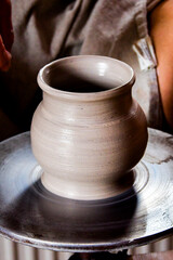 Hands in motion shaping clay on the potters wheel. Moment of creation at the wheel and ready...