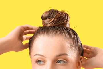 Young woman after washing hair on yellow background, closeup