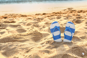 Stylish flips flops on sand near ocean at resort