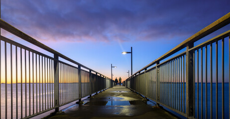 Murrays Bay wharf, a popular fishing spot. Unrecognizable people walking on the wharf. Auckland.